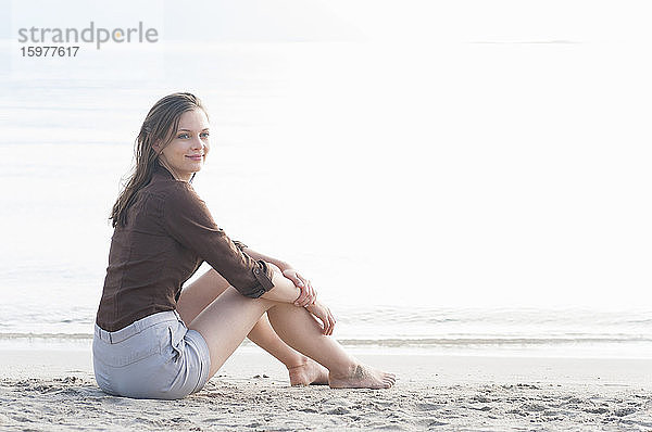 Porträt einer Frau  die am Strand vor dem Meer sitzt  Sardinien  Italien