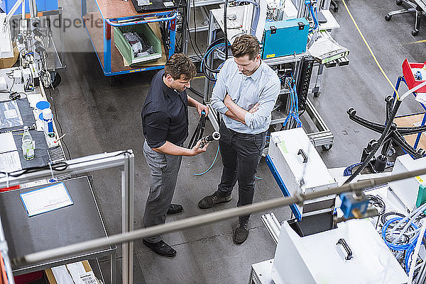 Zwei Männer bei einer Besprechung in einer Fabrik  die ein Produkt untersucht