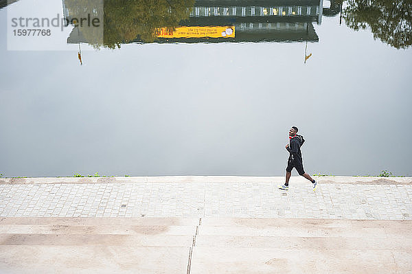 Junger Mann joggt am Flussufer