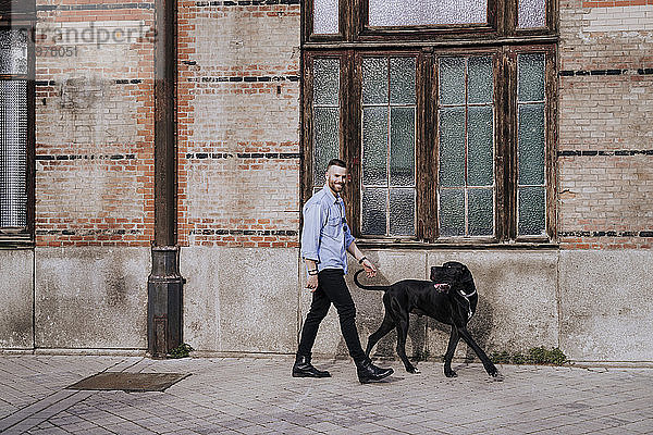 Lächelnder Mann geht mit seinem Hund spazieren