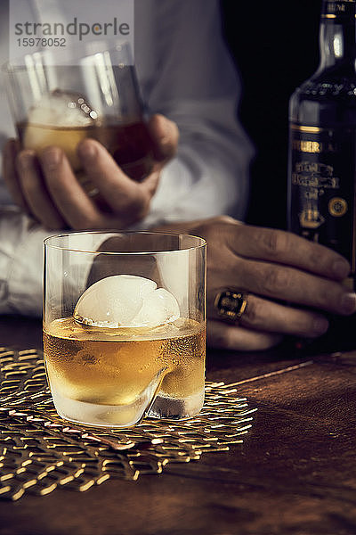 Scotch mit Eis  Männerhände im Hintergrund