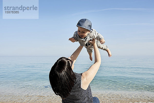 Mutter abholen glücklich niedlichen Sohn gegen Meer während sonnigen Tag