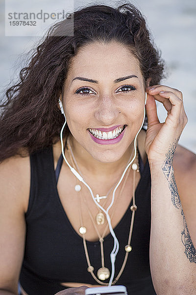 Porträt einer lächelnden jungen Frau mit Smartphone und Kopfhörern