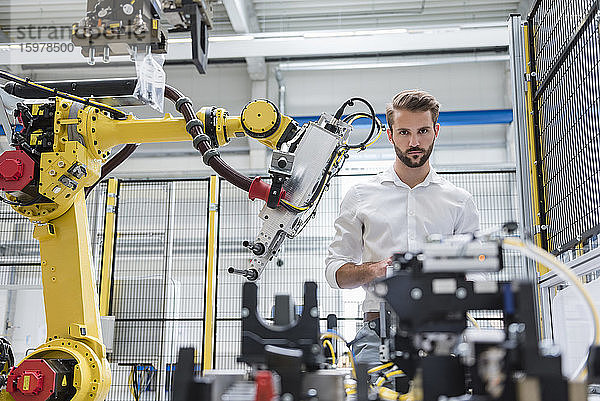 Selbstbewusster männlicher Robotikexperte  der sich Maschinen in der automatisierten Industrie ansieht