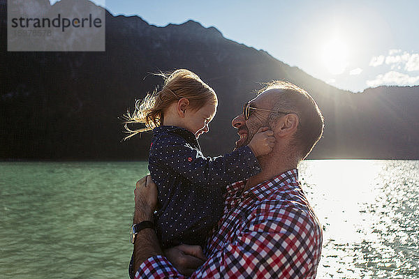 Vater trägt Tochter gegen Berg und See am Achensee  Bundesland Tirol  Österreich