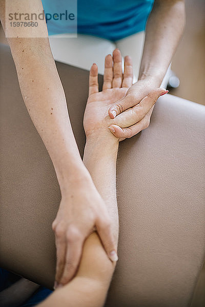 Weibliche Physiotherapeutin bei der Handmassage eines Patienten  Nahaufnahme