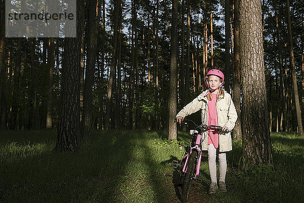 Mädchen stehend mit Fahrrad im Wald