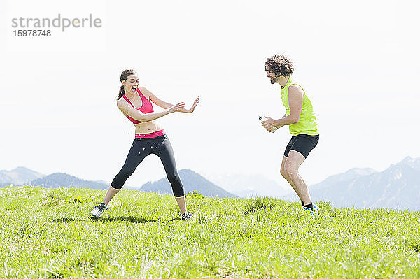 Jogger  der einer Frau Wasser spritzt  Wallberg  Bayern  Deutschland