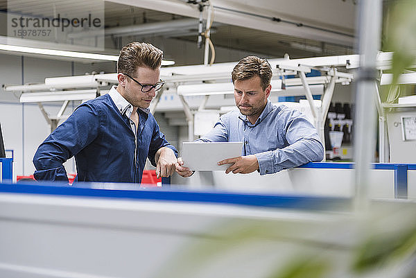 Zwei Männer teilen sich ein Tablet in einer Fabrik