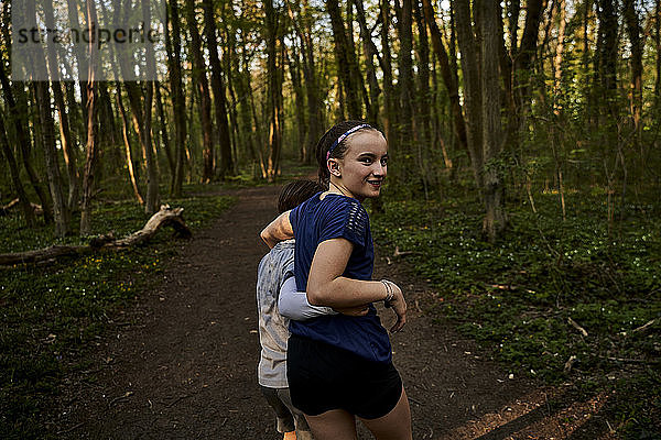 Lächelndes Mädchen mit Arm um Bruder im Wald