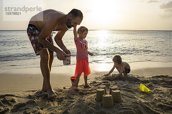 Vater spielt mit seinen Kindern am Strand bei Sonnenuntergang  Willemstad  Curacao