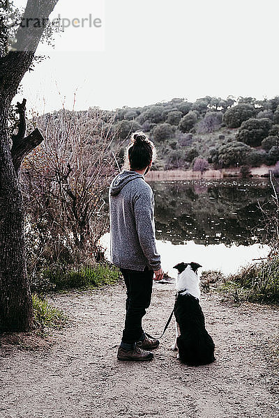 Mann mit seinem Hund am Seeufer