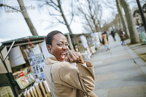 Aufmüpfige Frau zeigt Mittelfinger auf dem Bürgersteig in Paris  Frankreich