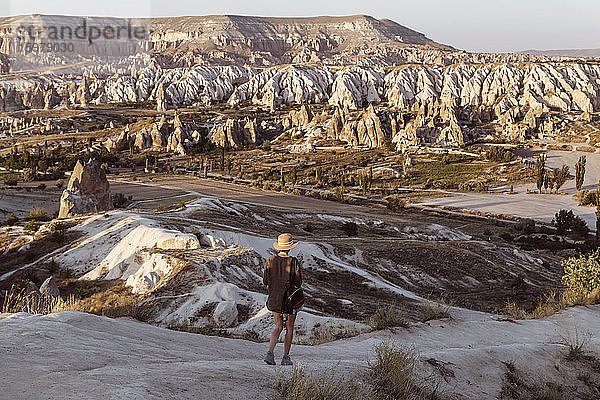 Rückansicht einer jungen Frau  die auf einer felsigen Landschaft in Goreme  Kappadokien  Türkei  spazieren geht