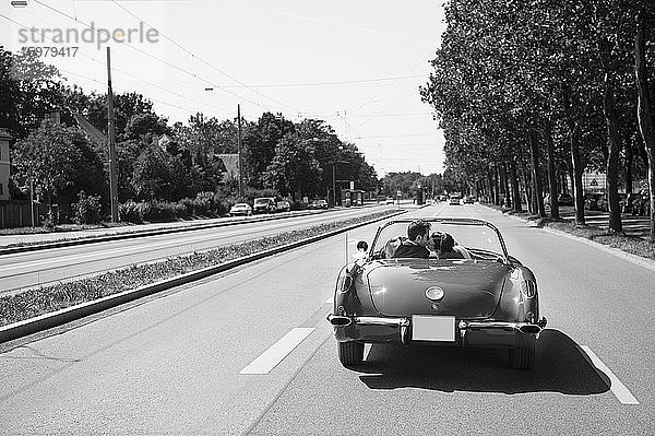 Küssendes Brautpaar in einem Cabrio