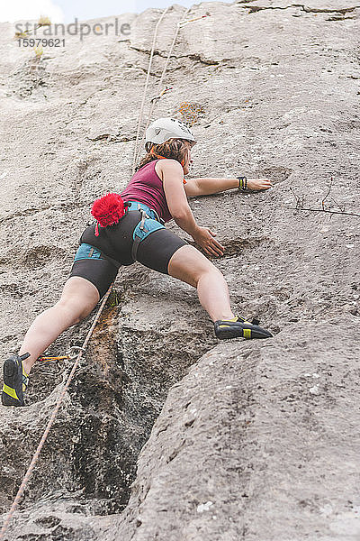 Junge Frau beim Klettern am Fels