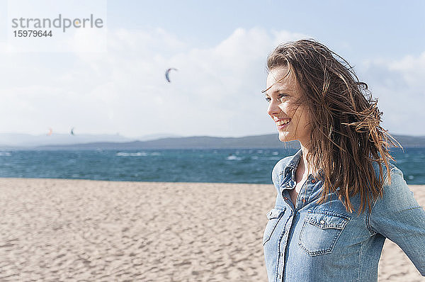 Porträt einer glücklichen Frau mit wehendem Haar am Strand  Sardinien  Italien