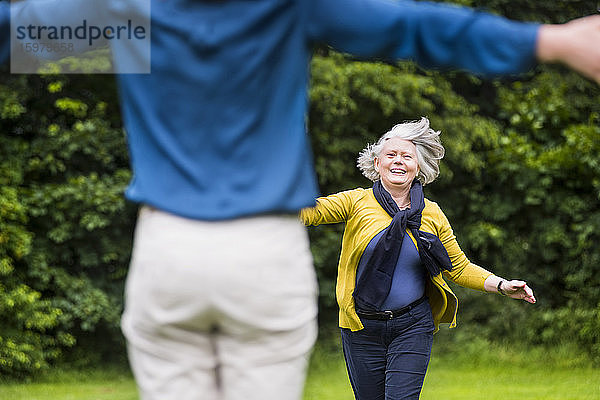 Porträt einer glücklichen älteren Frau  die zu ihrer erwachsenen Tochter in einem Park läuft