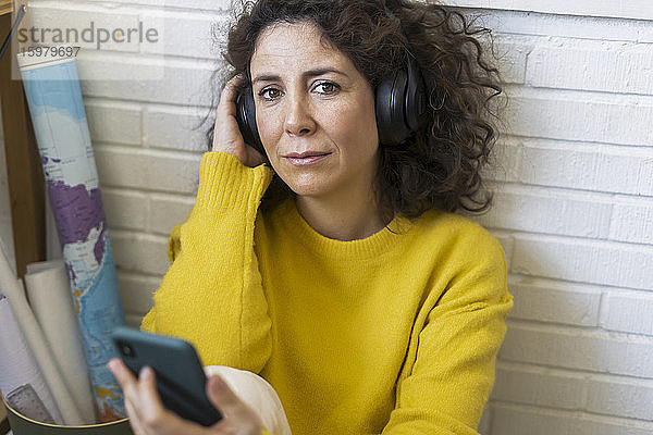 Porträt einer Frau mit Kopfhörern und Smartphone in der Hand