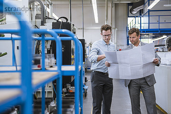 Zwei Geschäftsleute besprechen einen Plan in einer Fabrik