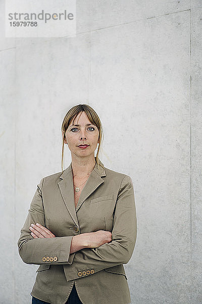 Porträt einer selbstbewussten Geschäftsfrau vor einer Betonwand