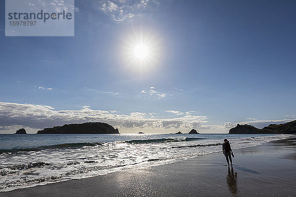 Neuseeland  Nordinsel  Waikato  Sonne scheint über die Silhouette einer allein stehenden Frau am Hahei Beach
