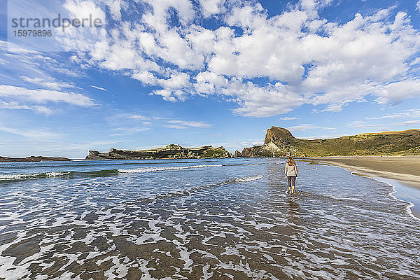 Neuseeland  Region Wellington  Castlepoint  Frau geht am Sandstrand des Pazifischen Ozeans entlang