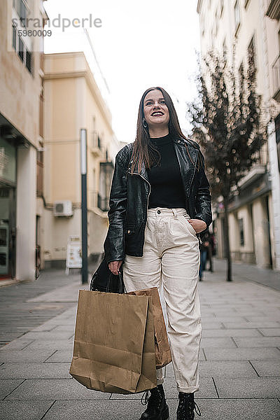 Porträt einer glücklichen jungen Frau mit Einkaufstüten in der Stadt