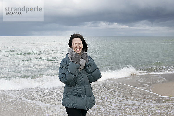 Russland  Kaliningrader Gebiet  Selenogradsk  Porträt einer jungen Frau  die am Küstenstrand steht und in die Kamera lächelt