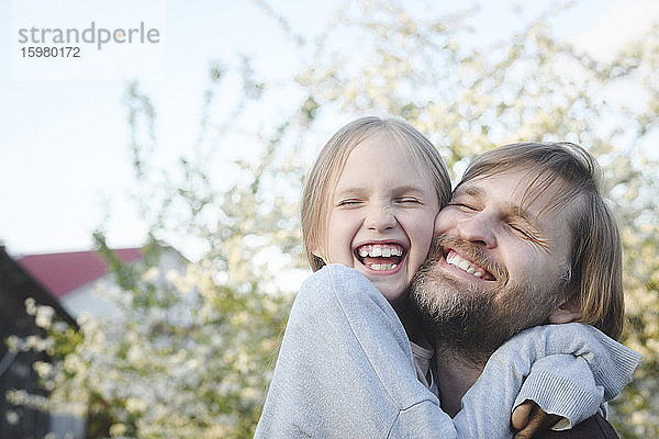 Nahaufnahme eines fröhlichen Mädchens  das seinen Vater im Hinterhof umarmt