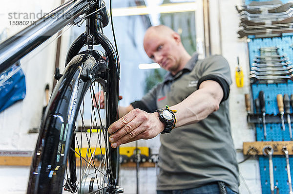 Fahrradmechaniker bei der Arbeit in einer Fahrradwerkstatt  Überprüfung des Vorderrads