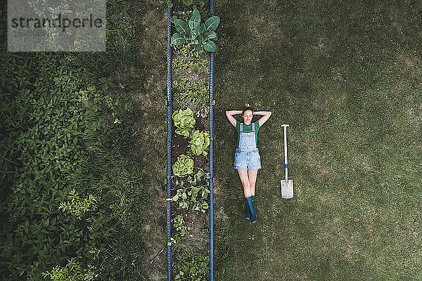 Luftaufnahme einer Frau  die an einem Hochbeet auf einem Grundstück im Hof liegt