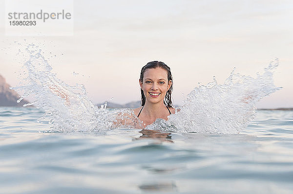 Porträt einer glücklichen Frau  die mit Wasser plantscht  Sardinien  Italien