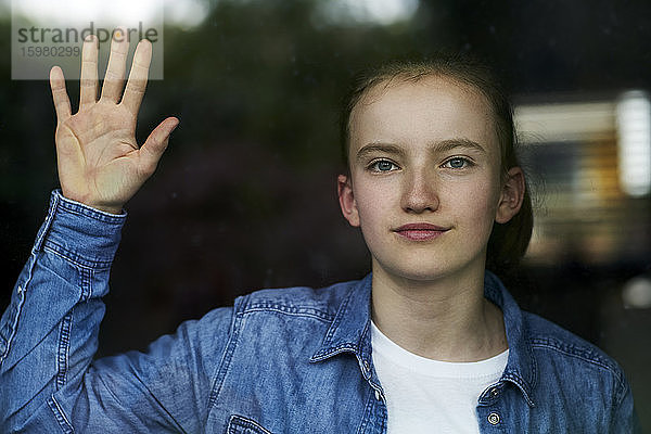 Nahaufnahme eines Mädchens durch eine Fensterscheibe gesehen