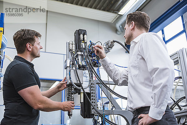 Zwei Männer bei einer Besprechung an einer Maschine in einer Fabrik