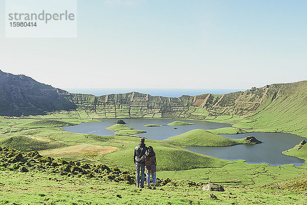 Rückansicht eines Paares mit Blick auf den See und die Berge bei klarem Himmel an einem sonnigen Tag  Corvo  Azoren  Portugal