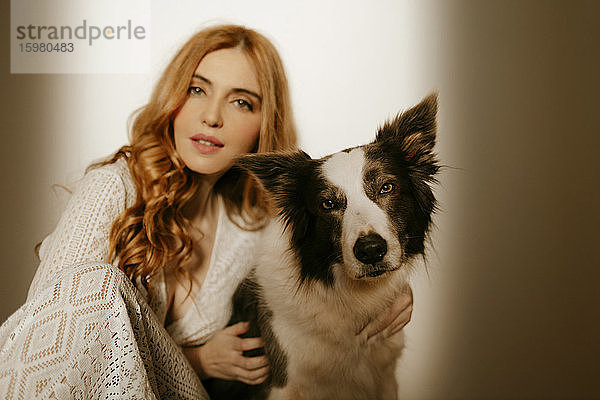 Blonde Frau zu Hause im Pijama mit einem Border Collie Hund