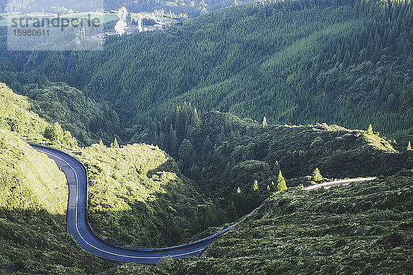 Blick von oben auf eine kurvenreiche Bergstraße in der Nähe eines grünen Waldes  San Miguel  Azoren  Portugal