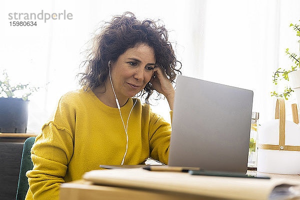 Frau mit Laptop am Schreibtisch im Heimbüro