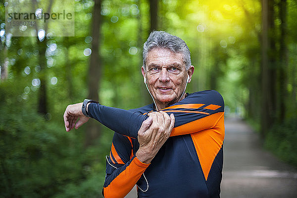 Porträt eines selbstbewussten älteren aktiven Mannes  der sich im Park streckt