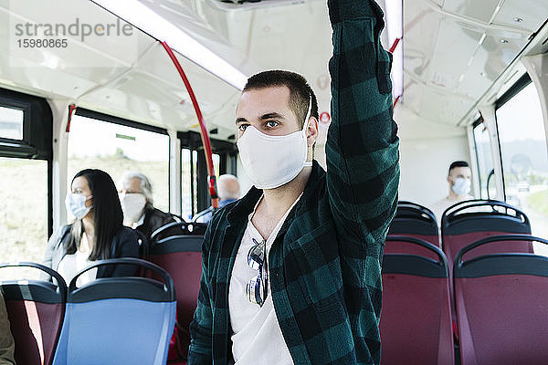 Porträt eines jungen Mannes mit Schutzmaske in einem öffentlichen Bus  Spanien