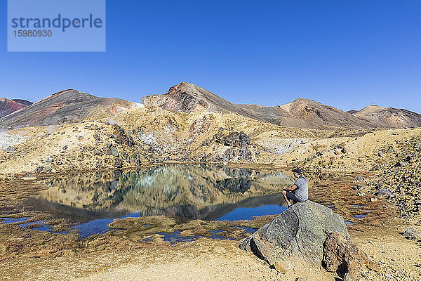 Neuseeland  Nordinsel  Männlicher Wanderer entspannt sich an den Emerald Lakes in der vulkanischen Hochebene der Nordinsel