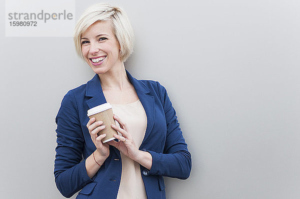 Porträt einer blonden Geschäftsfrau mit Kaffee zum Mitnehmen
