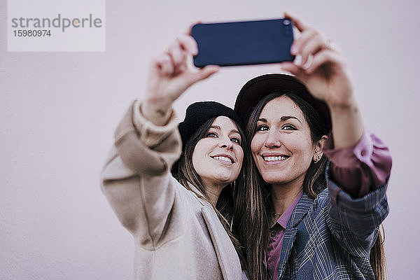 Porträt von zwei glücklichen Frauen  die ein Selfie mit einem Smartphone machen