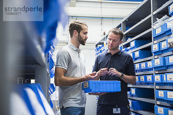 Zwei Männer unterhalten sich in einer Lagerhalle einer Fabrik