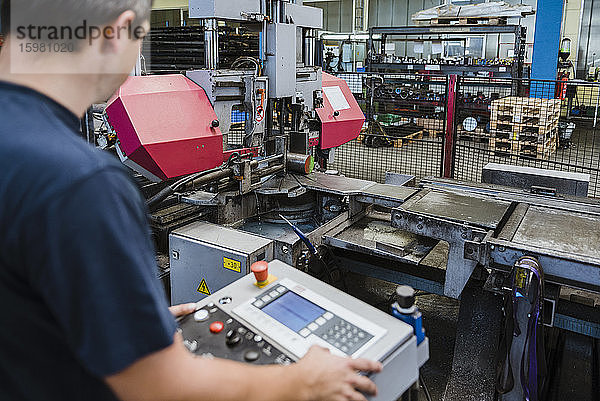 Ein Mann bedient eine Maschine in einer metallverarbeitenden Fabrik