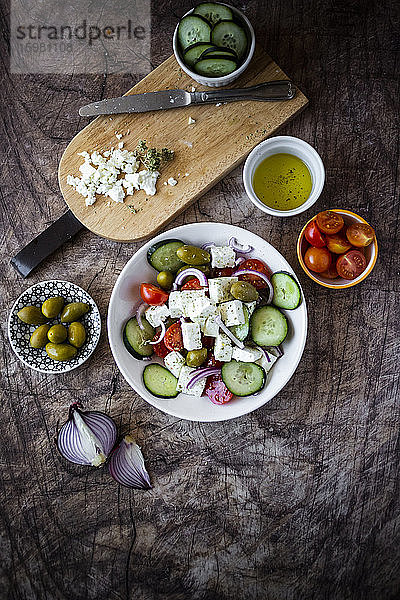 Schüssel mit verzehrfertigem griechischem Salat und seinen Zutaten