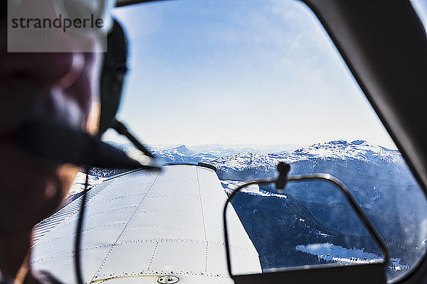 Österreich  Tirol  Steinberg am Rofan  Pilot schaut durch das Fenster während des Fluges über das Gebirge