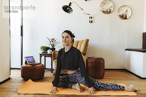 Junge Frau übt Yoga zu Hause