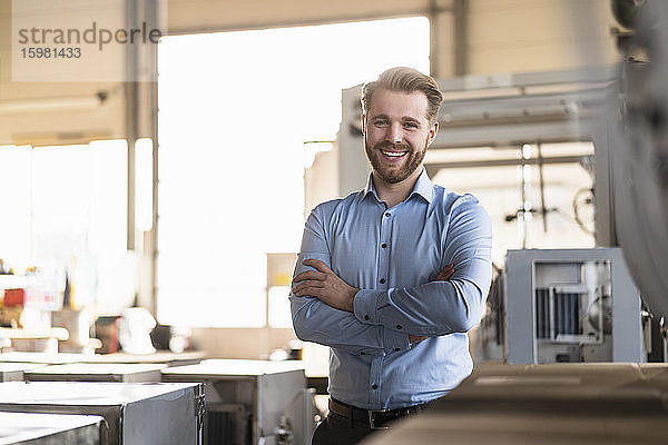 Porträt eines glücklichen jungen Geschäftsmannes in einer Fabrik